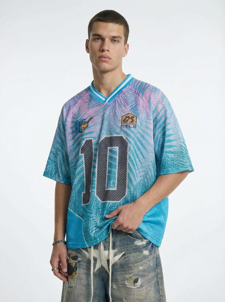 Model wearing a pastel blue and pink mesh jersey T-shirt with a large number 10 and tropical palm print details