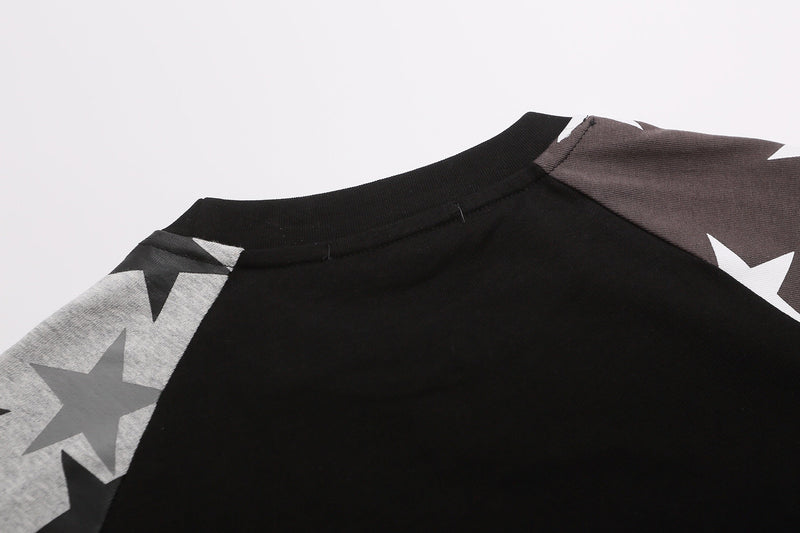 Close-up of a black raglan tee with oversized star graphics and a contrasting brown sleeve, styled for Y2K streetwear