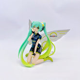 The Racing Butterfly Hatsune Miku 12cm PVC Figure by Hatsune Miku showcases her kneeling with turquoise twin tails, a black outfit with colorful accents, green boots, and yellow-silver Racing Butterfly wings featuring "TeamUKYO" and "ZENRIN" logos.