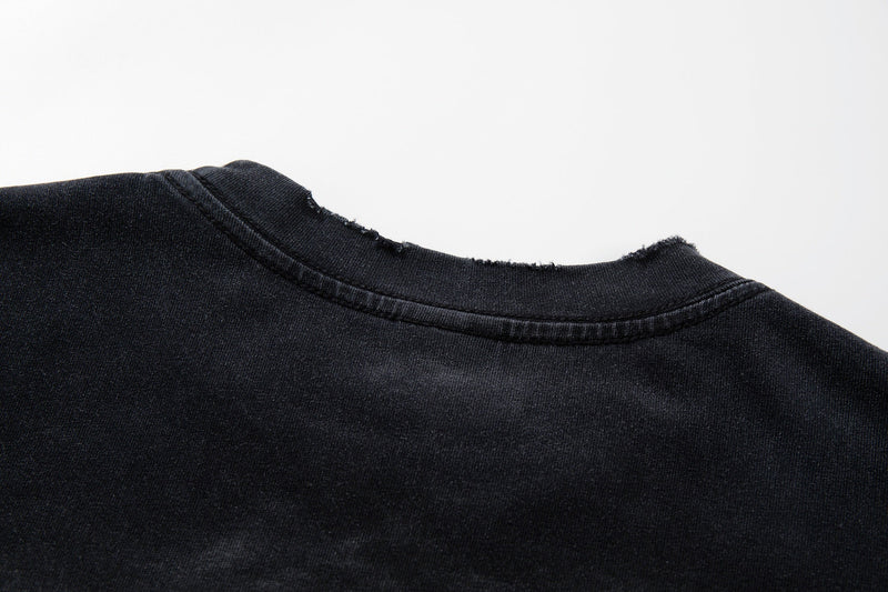 Close-up of a washed black graphic tee collar with frayed edge and vintage worn texture