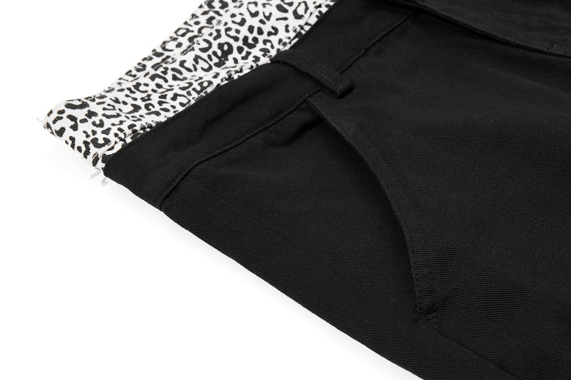 Close-up of black pants waistband and front pocket seam with leopard-print trim
