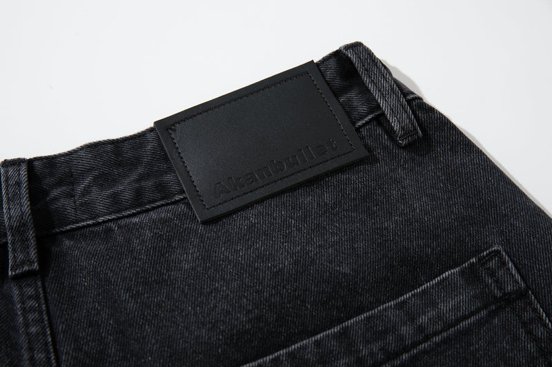 Back waistband detail with black logo patch and belt loops on washed charcoal denim