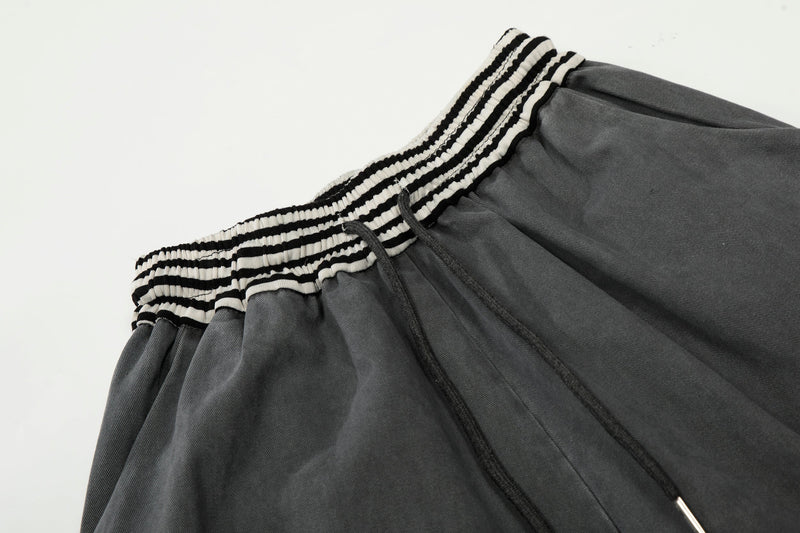 Close-up of striped elastic waistband with black drawstring on washed charcoal pants