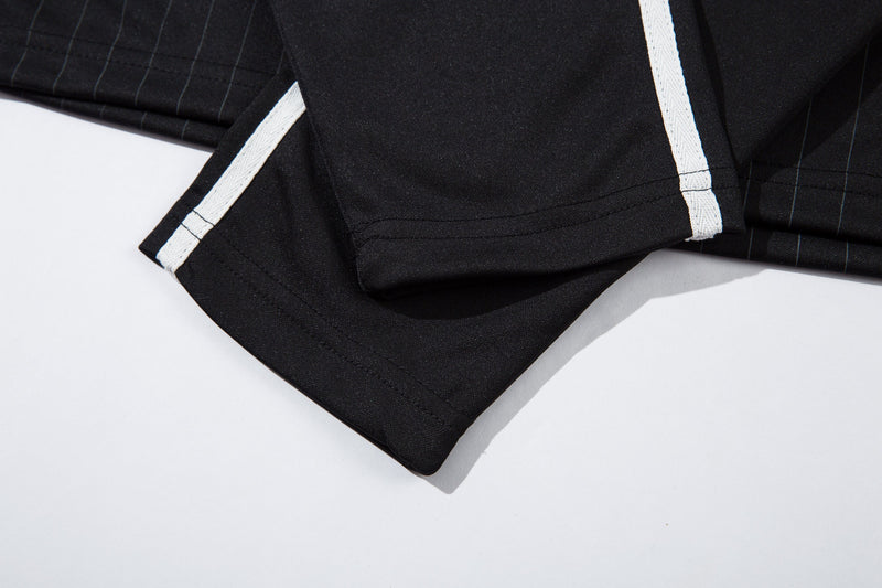 Close-up of black jersey sleeve cuff with white side stripe detail