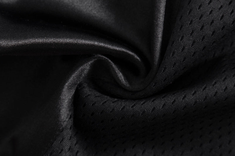 Close-up of black satin and mesh fabric folds showing glossy texture