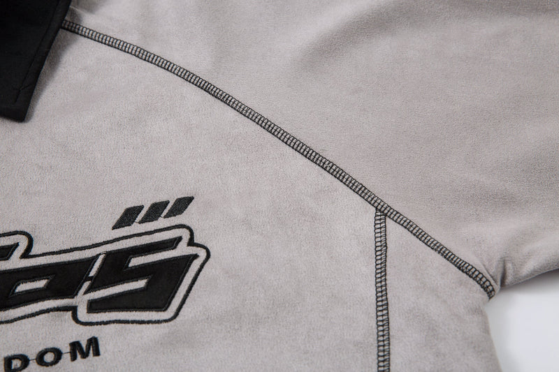 Close-up of contrast seam stitching on the light gray shirt shoulder and side panel