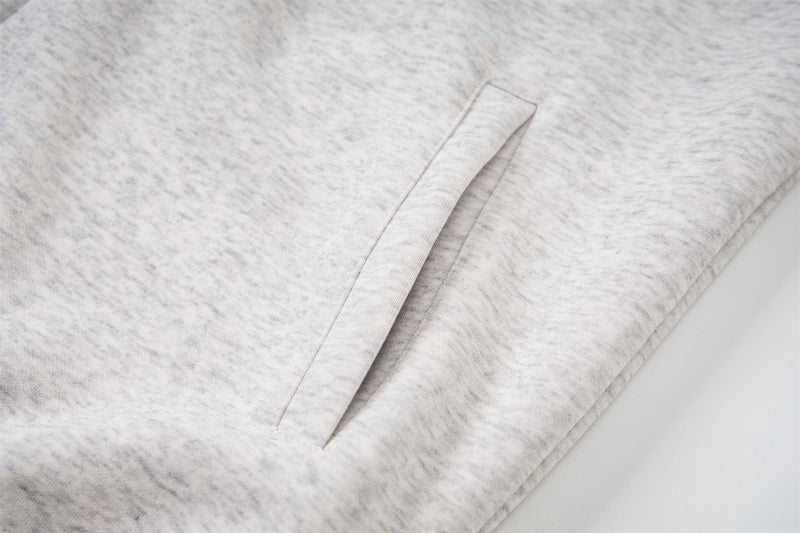 Close-up of a light gray hoodie side pocket opening and heathered fabric