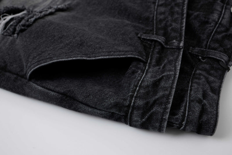 Close-up of black denim shorts hem with folded cuff and seam stitching