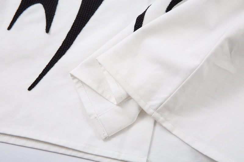 Close-up of layered white sleeve over black long sleeve at the elbow