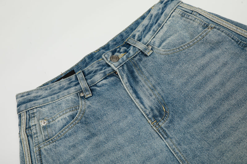 Close-up of light wash denim waistband with front button, belt loops, and topstitching
