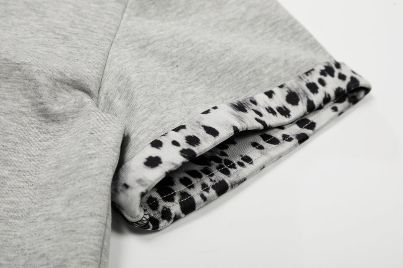 Close-up of a gray quarter-zip polo shirt with leopard print trim and folded cuff detail