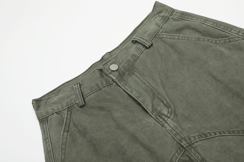 Close-up of olive green pants waistband with belt loops, snap button and seam detail