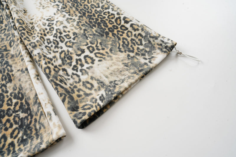 Close-up of wide pant leg hem with drawcord toggle on leopard print pants