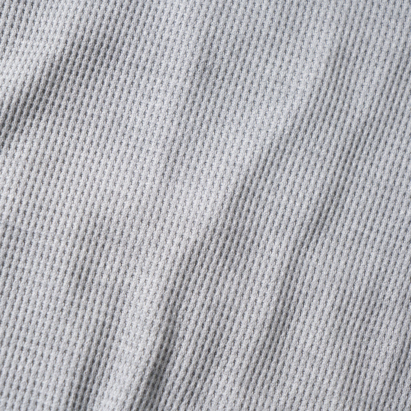 Close-up of the waffle knit fabric texture on the light gray hoodie