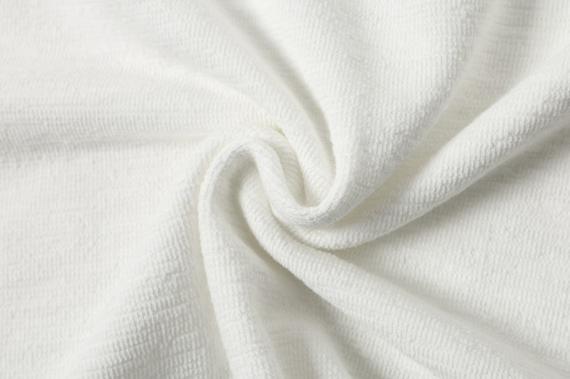 Close-up of white textured polo shirt fabric with soft knit weave and subtle folded swirl detail
