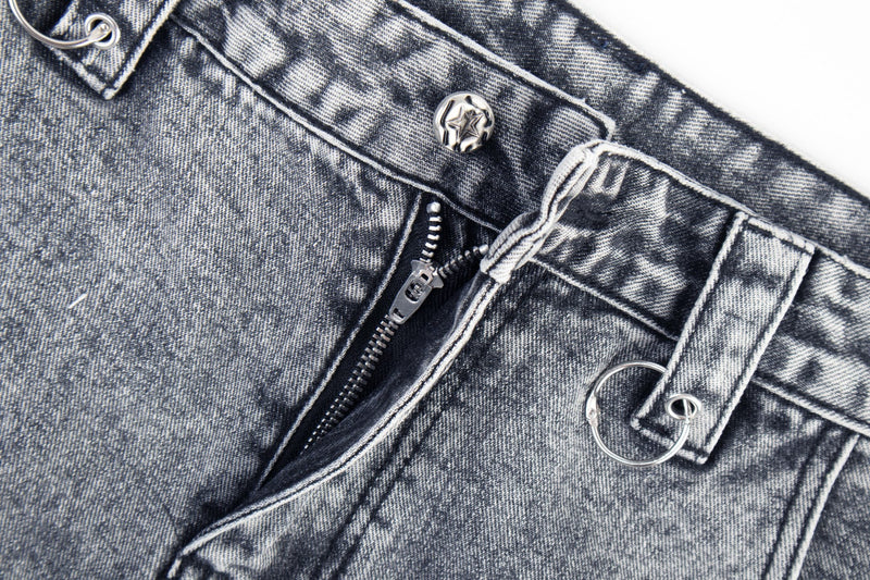 Close-up of denim waistband with star button, belt loops, and zipper pocket