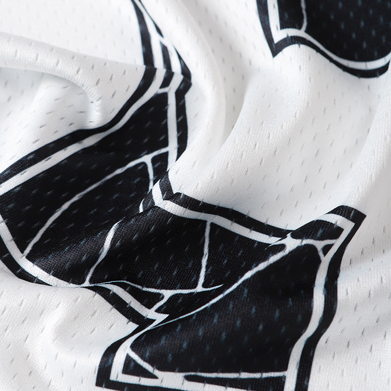 Close-up of black spider web graphic on white mesh football jersey fabric, dark streetwear top