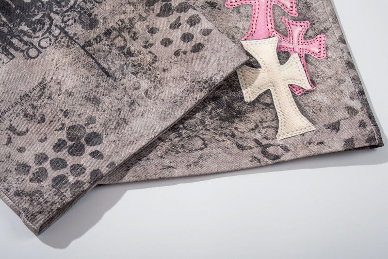Close-up of hem on washed gray denim shorts with pink and white cross patch