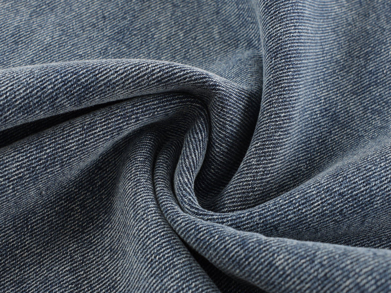 Close-up of blue denim fabric folds with visible diagonal twill texture