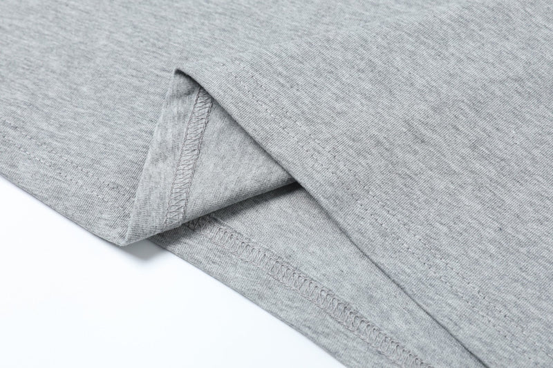 Close-up of a light gray structured short-sleeve T-shirt with folded hem and visible stitched seams on soft knit fabric