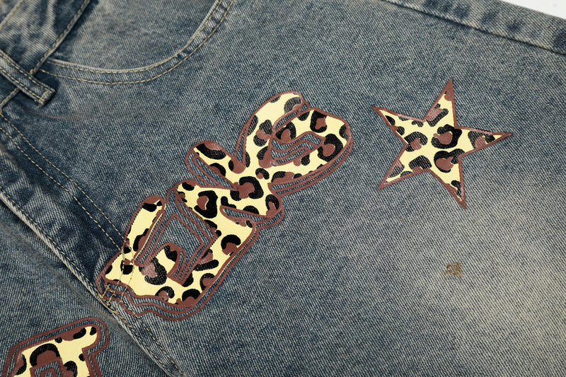 Close-up of leopard print word and star graphic across the back of blue jeans