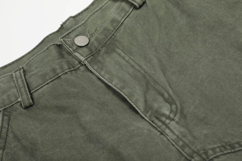 Close-up of olive green pants front waistband with snap button and topstitched seam
