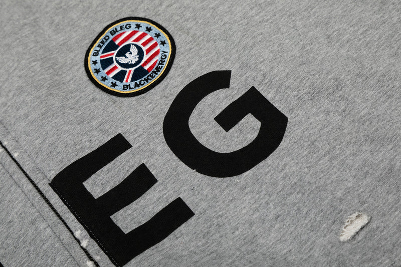 Close-up of round embroidered chest patch and BLEG front print on gray hoodie