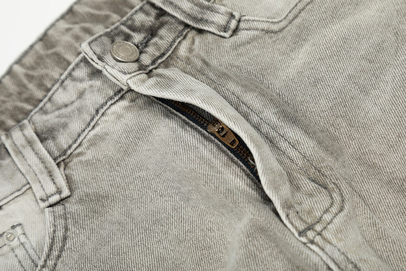 Close-up of front zipper and button closure on light gray jeans