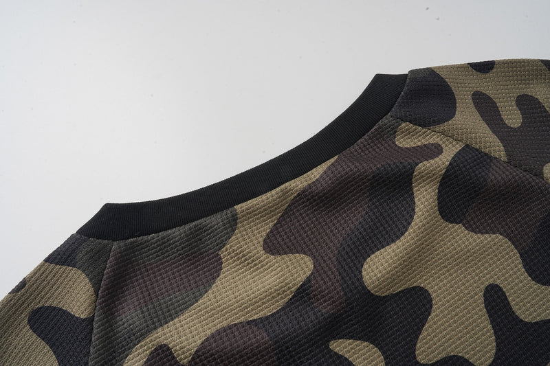 Close-up of camo jersey shoulder and black ribbed collar on textured fabric
