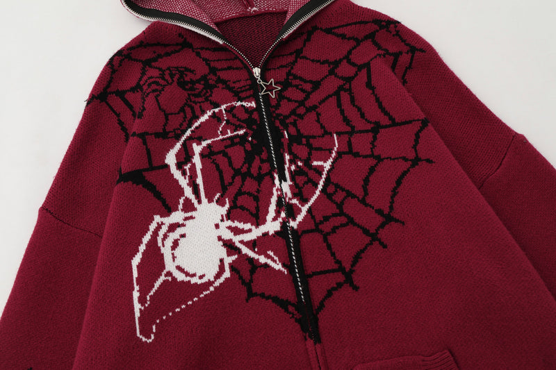 Close-up of burgundy hoodie front with black spiderweb knit and white spider graphic