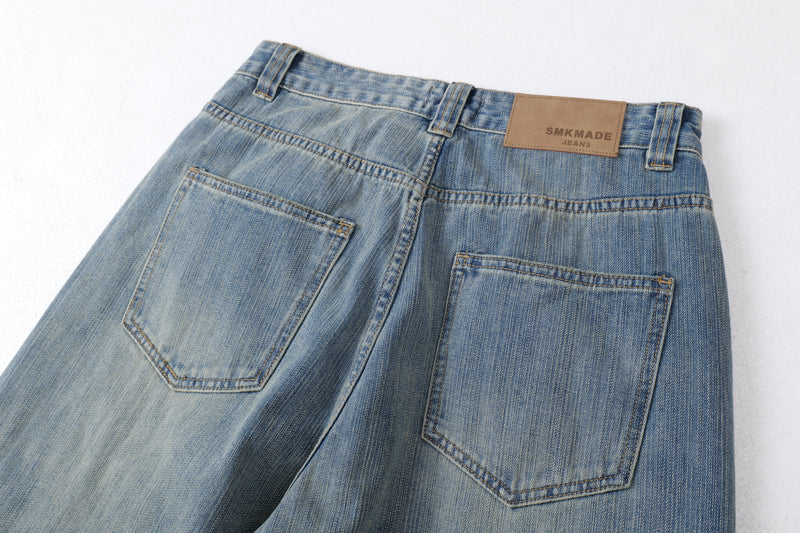 Close-up of the back waistband and pockets on faded blue jeans with tan leather label