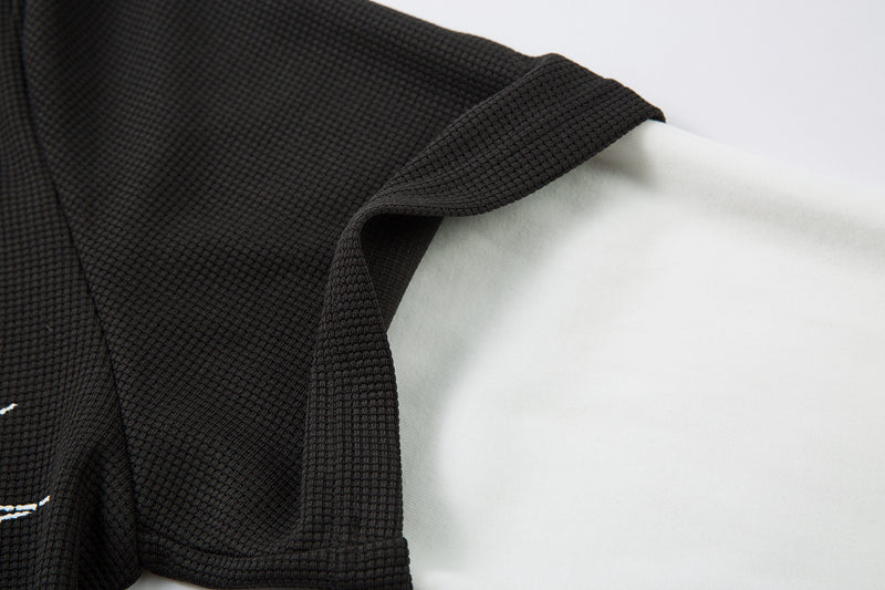 Side view of black textured short sleeve layer over white long sleeve shirt