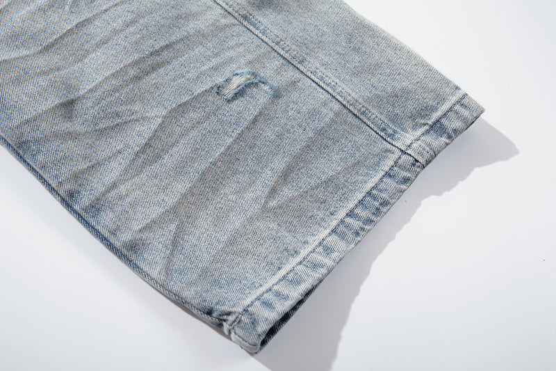 Close-up of hem on light wash denim jeans with faded wash and small distress mark