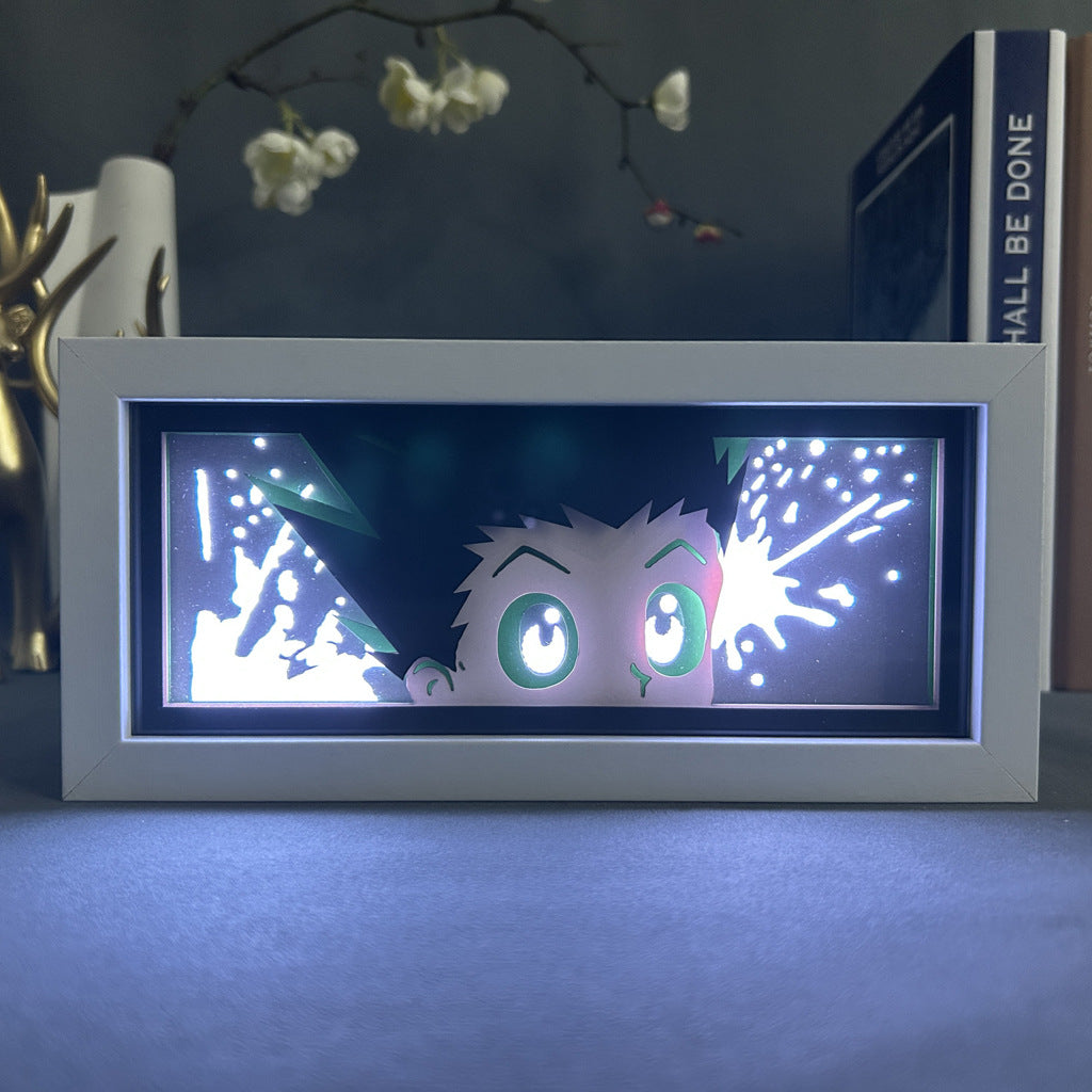 The Hunter × Hunter Anime Light Box is a 3D LED lamp featuring Gon Freecss with his green eyes and spiky hair, showcasing his face looking up in surprise. The dynamic color-changing effects and white accents suggest movement or action.