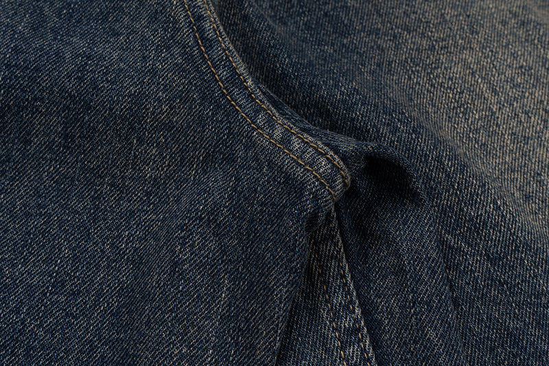 Close-up of blue denim seam and pocket opening with faded wash