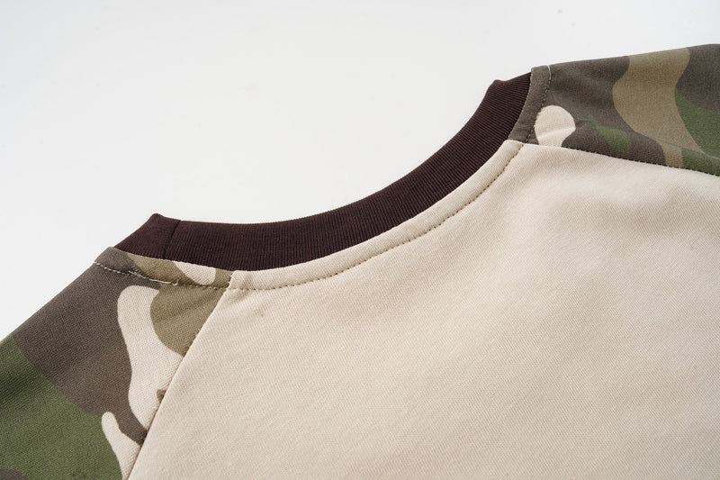 Close-up of a camo raglan T-shirt with beige body, brown ribbed collar, and olive camouflage sleeves