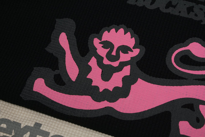 Close-up of a black waffle tee with bold pink vintage newspaper-style graphic print on textured fabric