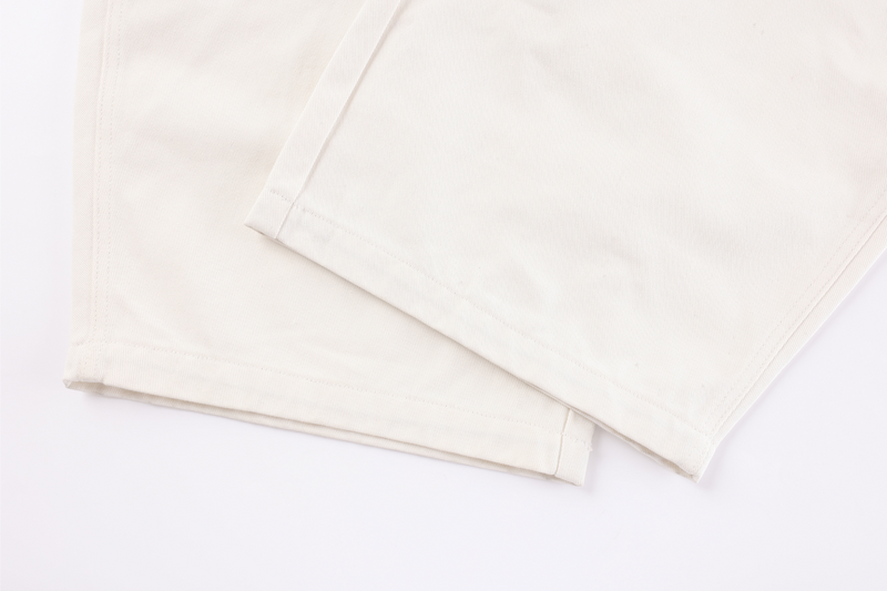 Cropped hems of cream barrel-leg jeans