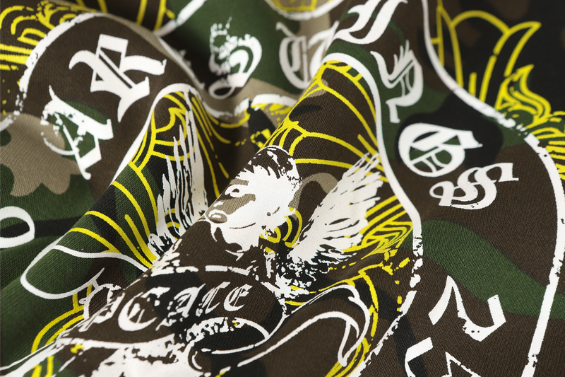 Close-up of layered white and yellow angel print on camo hoodie fabric