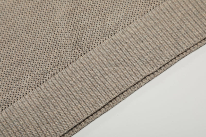 Close-up of a beige open knit polo shirt with ribbed trim and breathable textured cotton fabric