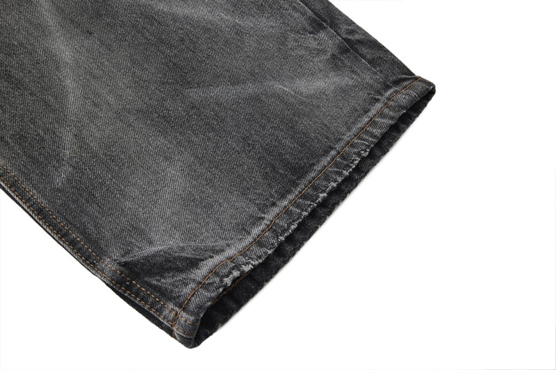 Close-up of hem on faded black wide-leg jeans with raw edge and stitched cuff