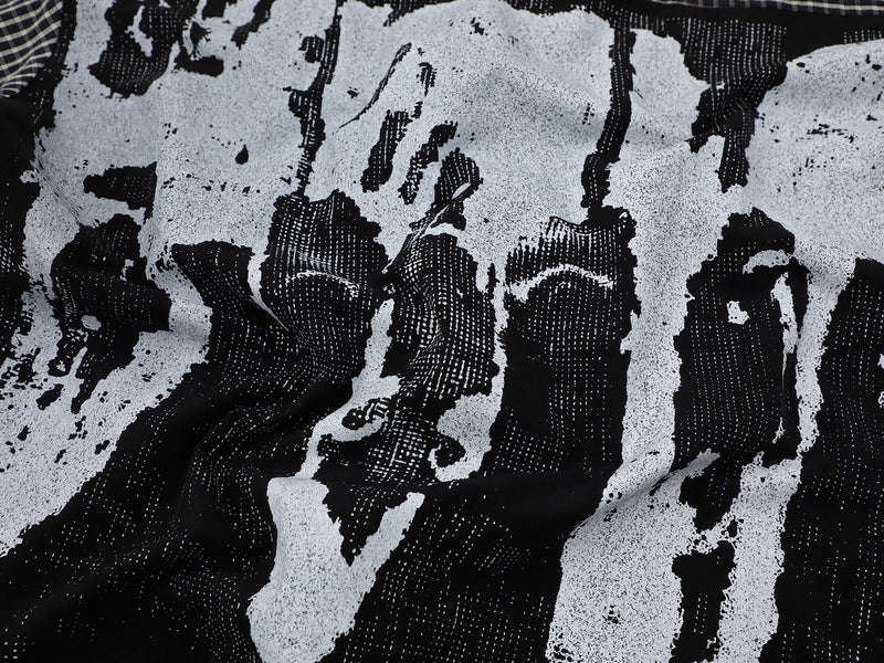 Black and white plaid shirt fabric with abstract graphic print and textured streetwear pattern close-up