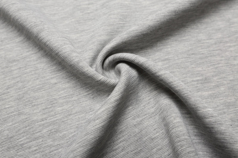 Close-up of soft light gray cotton fabric with fine knit texture and smooth folded drape