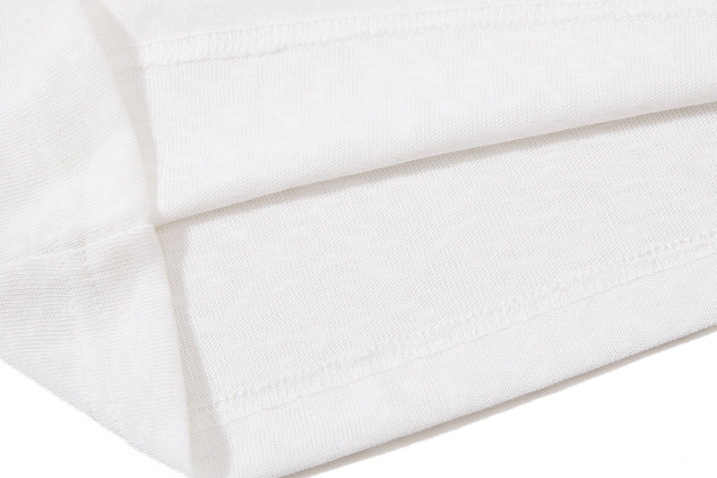 Close-up of white polo shirt fabric with stitched hem and textured knit material