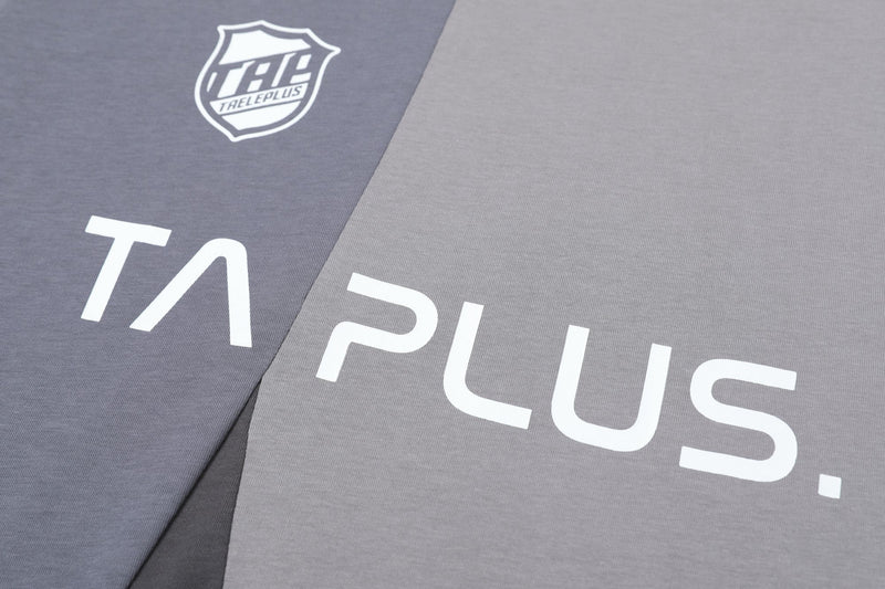Grey split-panel graphic tee with bold white TA Plus lettering and shield logo print on soft cotton fabric