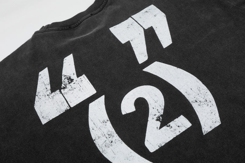 Black vintage washed graphic tee with distressed white abstract lettering on the chest, close-up streetwear detail