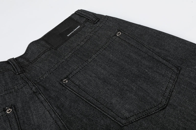 Close-up of back pocket and waistband label on black raw denim baggy shorts