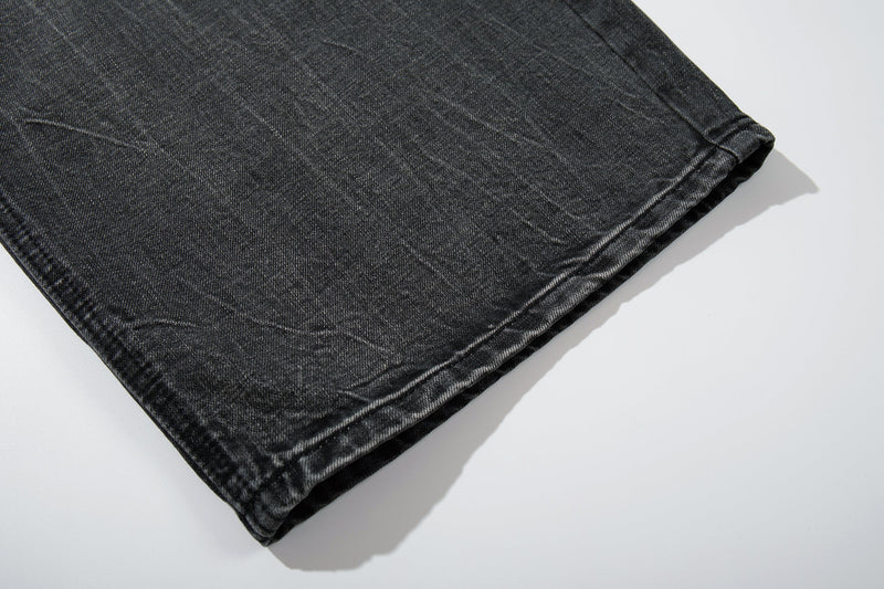 Close-up of the hem on black wide-leg jeans with faded wash and folded cuff