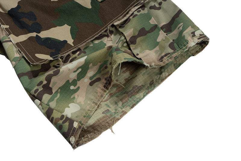 Close-up of lower hem and side seam on camouflage cargo shorts with raw edges