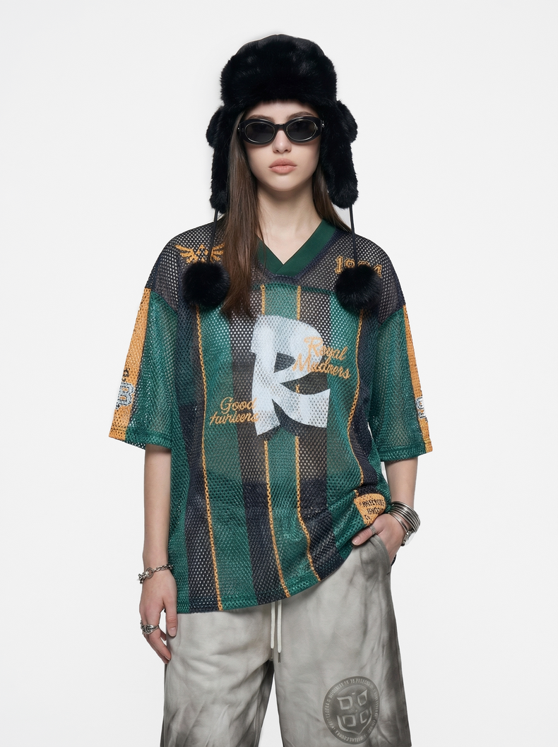 Model wearing a green and black mesh jersey T-shirt with bold graphic print and streetwear styling